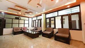 A modern living room with a glass coffee table, sofas, and a ceiling fan. - Fabhotel Kempty Lake Resort (Dhanaulti)