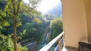 A balcony with a view of a waterfall and dense greenery. - Fabhotel Kempty Lake Resort (Dhanaulti)