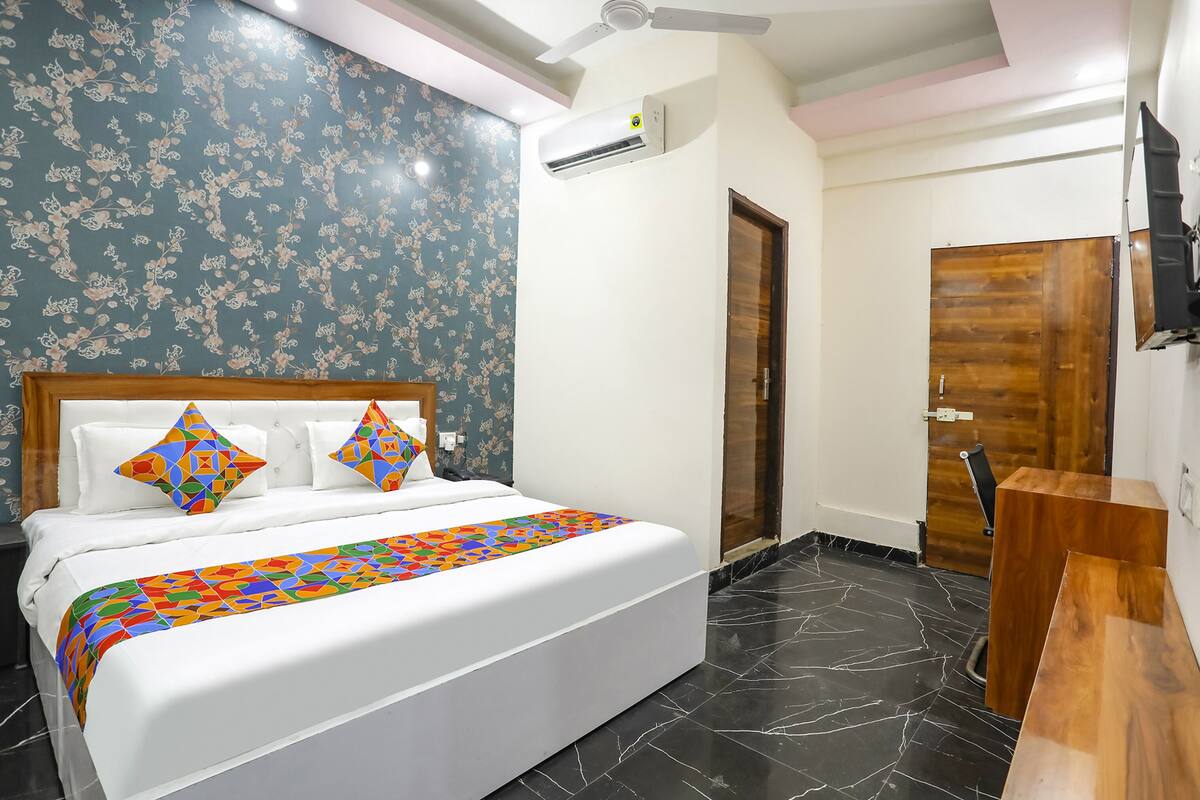 Une chambre à coucher avec un lit, un ventilateur de plafond, un climatiseur, une porte en bois et un banc en bois.