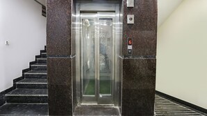 En elevator med digitalt display, knap Panel og glasdør.
