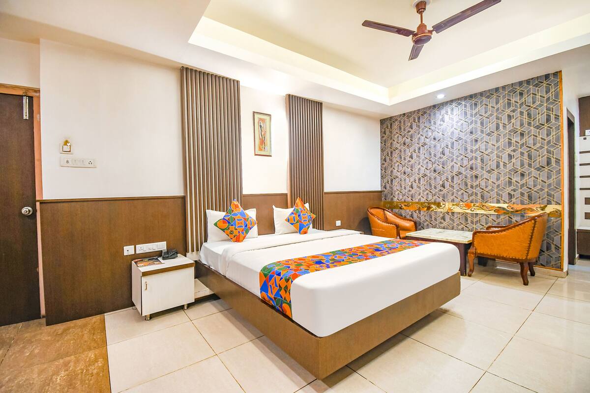 Habitación de hotel con cama, mesita de noche, silla y decoración en la pared.