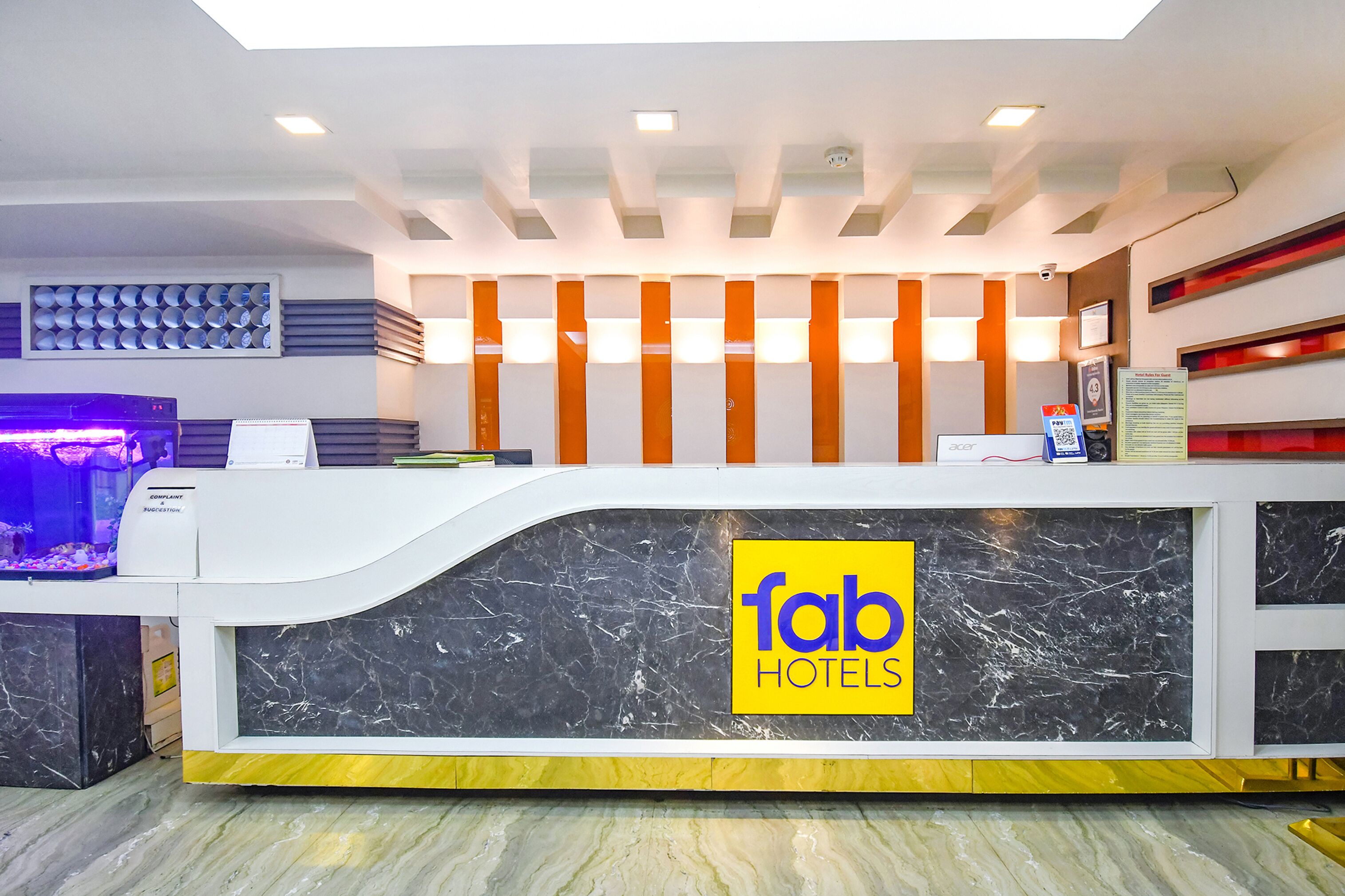 A hotel reception desk with a marble counter, a fish tank, and a sign for 'fab hotels'.