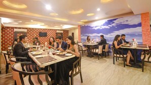 A restaurant with round tables and chairs, a patterned wall, and a large mural of a sky. - Fabhotel Emerald (Ranchi)