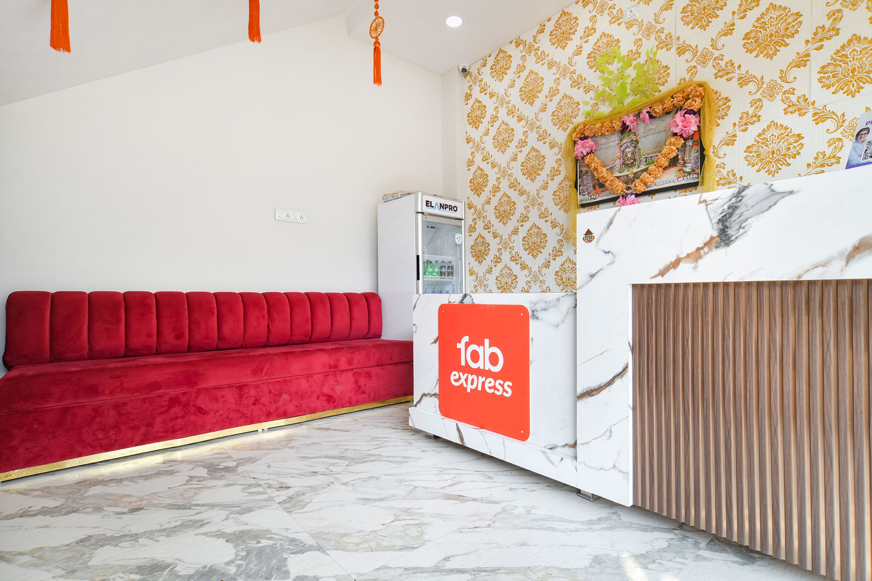 A reception area with a red sofa, a marble reception desk, and a patterned wall.