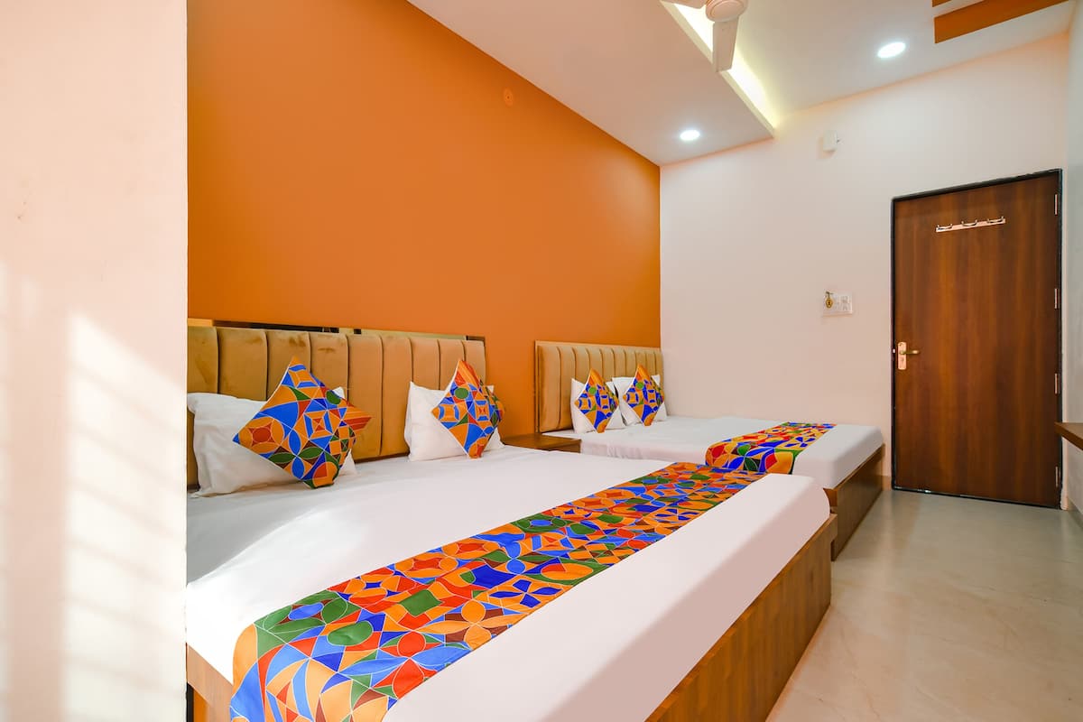 A hotel room with two beds, orange walls, wooden headboards, and a wooden door.