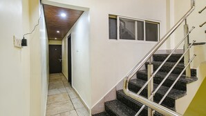 A staircase with metal railings and black steps, leading to a landing with a window. - Fabexpress Brahmasmi (Ujjain)
