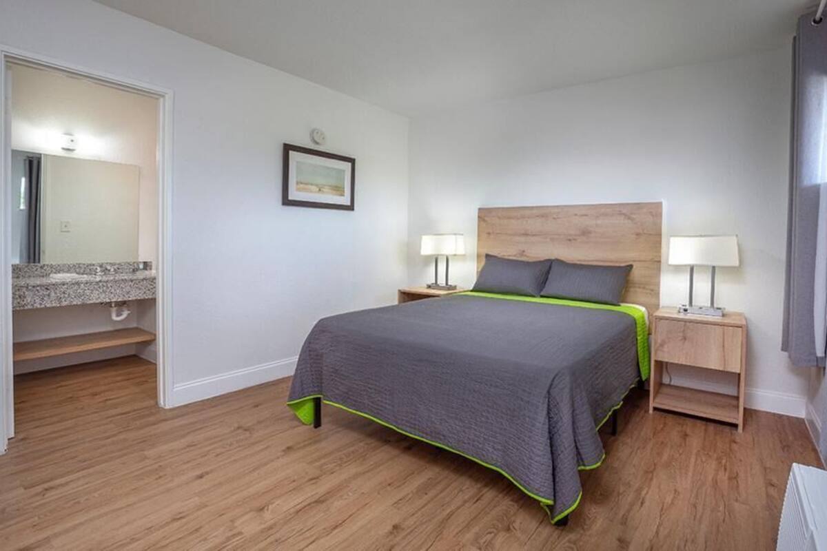 A bedroom with a bed, bedside tables, a mirror, and a door leading to a bathroom.