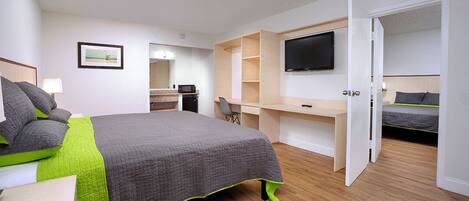 Quarto com cama, escrivaninha, televisão e closet espaçoso.
