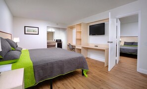 A modern bedroom with a bed, a desk, a TV, and a separate sleeping area.