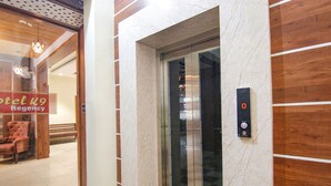 En elevator med digitalt display, marmorvæg og træpanel.