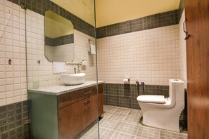 A bathroom with a white sink, a mirror, a toilet, and a shower area.