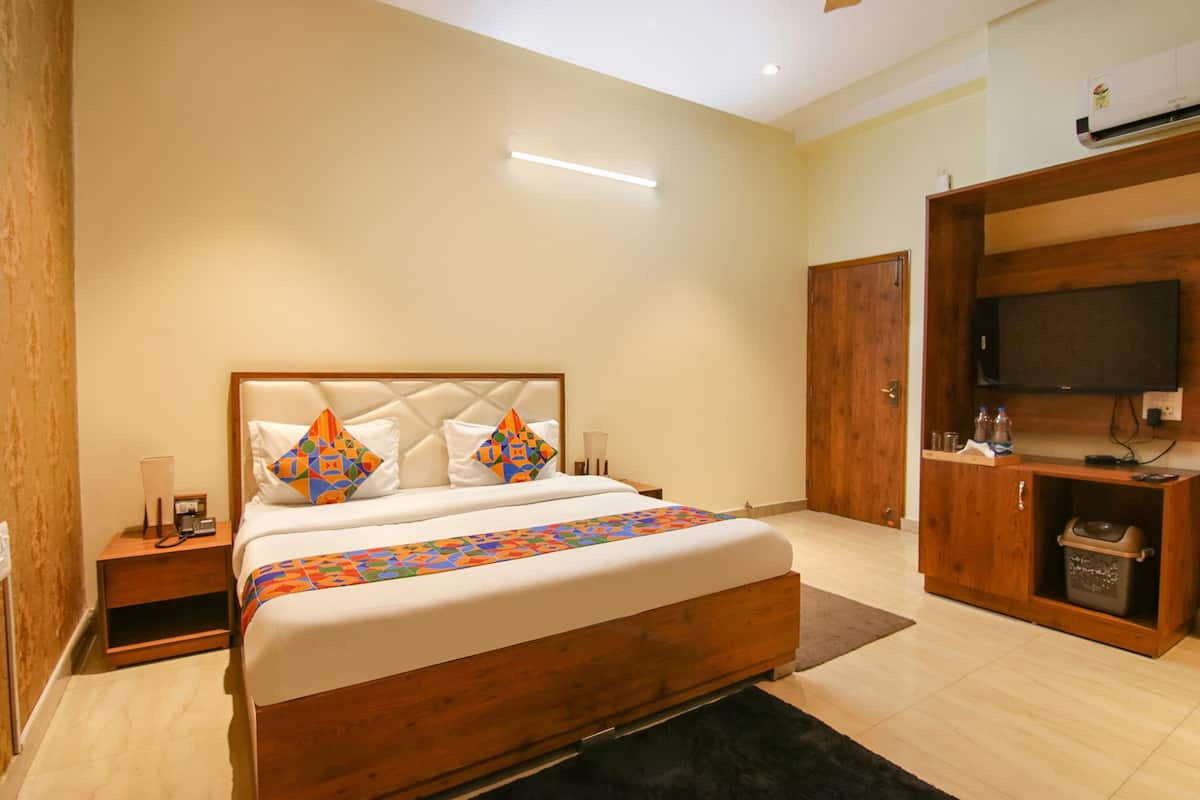 A hotel room with a wooden bed, a TV, a wardrobe, and a bedside table.