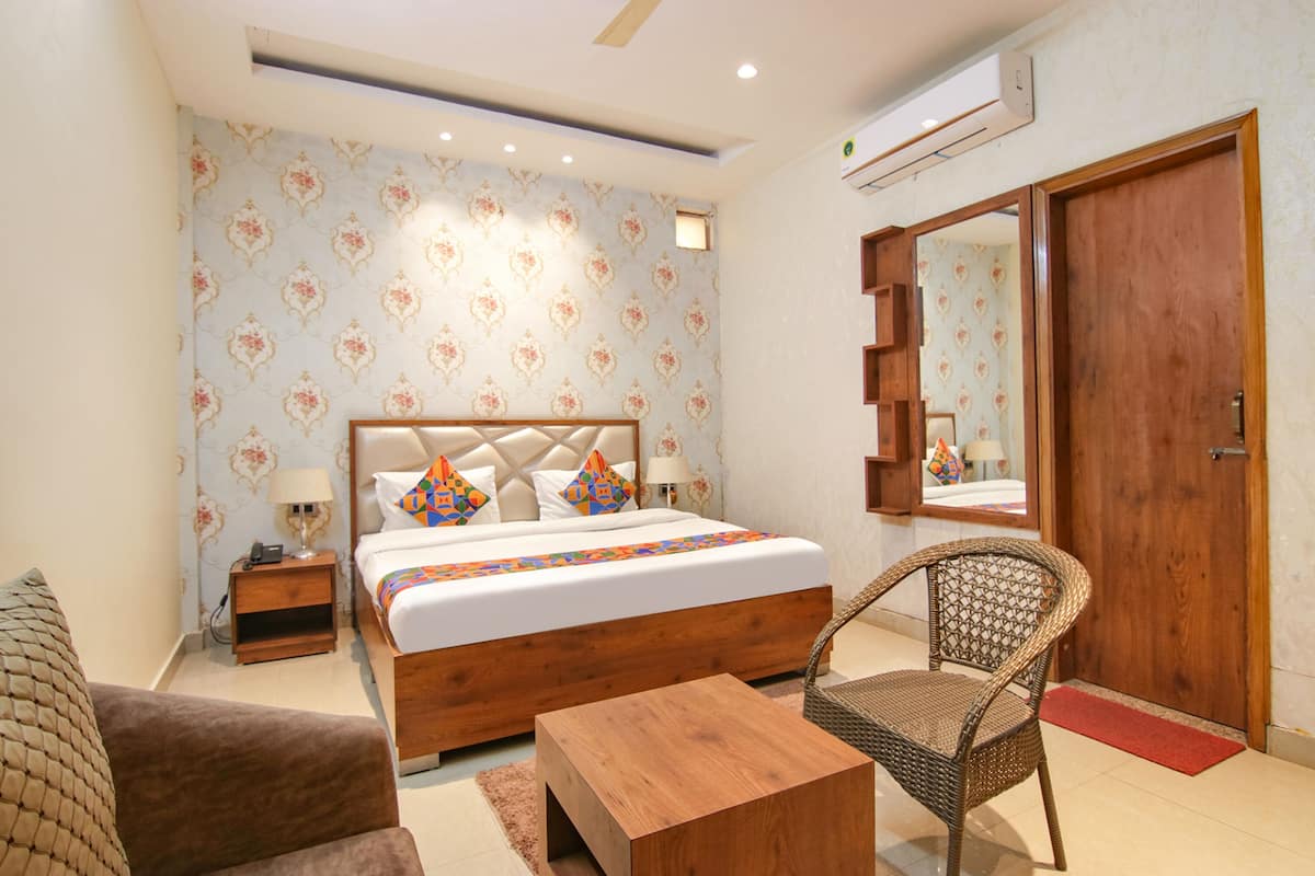 A bedroom with a bed, bedside table, chair, and a wooden coffee table.