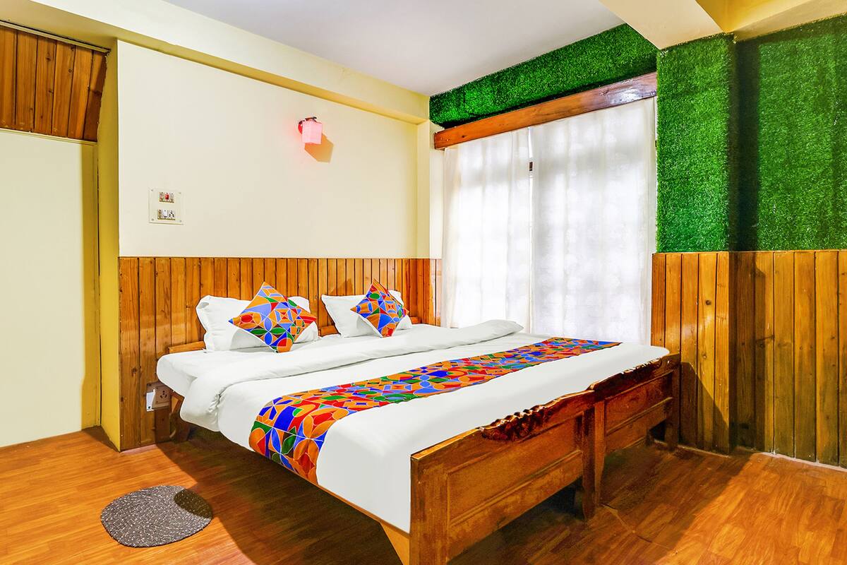 A bedroom with a wooden bed, a colorful bedspread, and a green wall accent.
