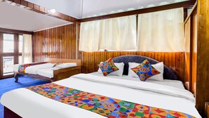 A hotel room with a large bed, a smaller bed, wooden paneling, a window with curtains, and a view of the outside. - Fabhotel Siljong (Gangtok)