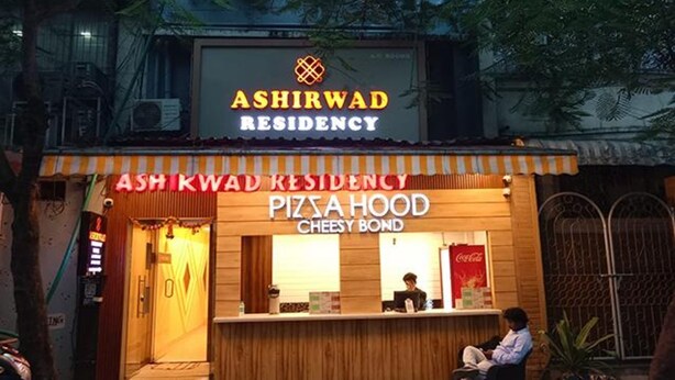 A pizza restaurant named Ashirwad Residency with a wooden facade and a Coca-Cola sign. - Fabexpress Ashirwad Residency Arn To Gst (Mumbai)