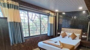 A bedroom with a bed, curtains, a window, and a tiled wall. - Fabexpress Ashirwad Residency Arn To Gst (Mumbai)