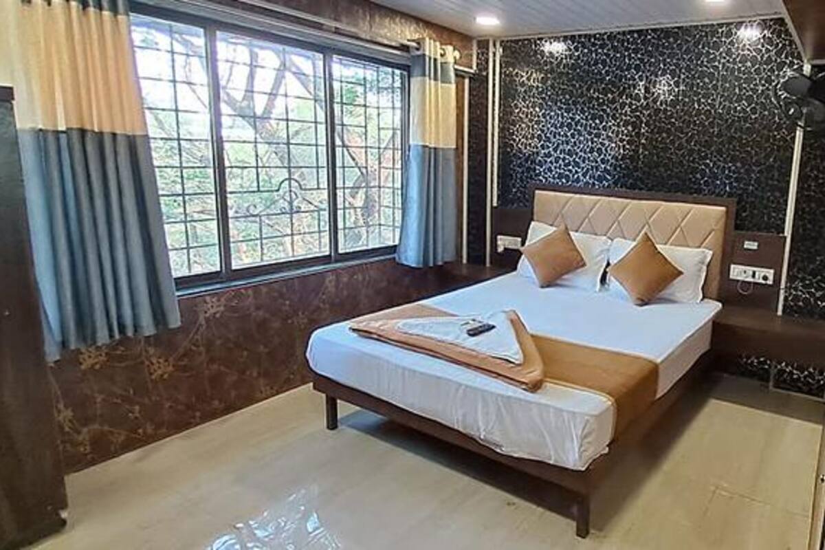 A bedroom with a large bed, a window with curtains, and a dark patterned wall.