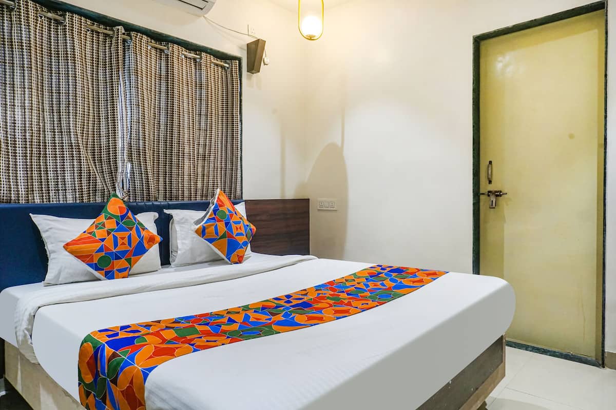 Cama bem arrumada com colcha estampada, cabeceira e duas almofadas com desenhos geométricos.