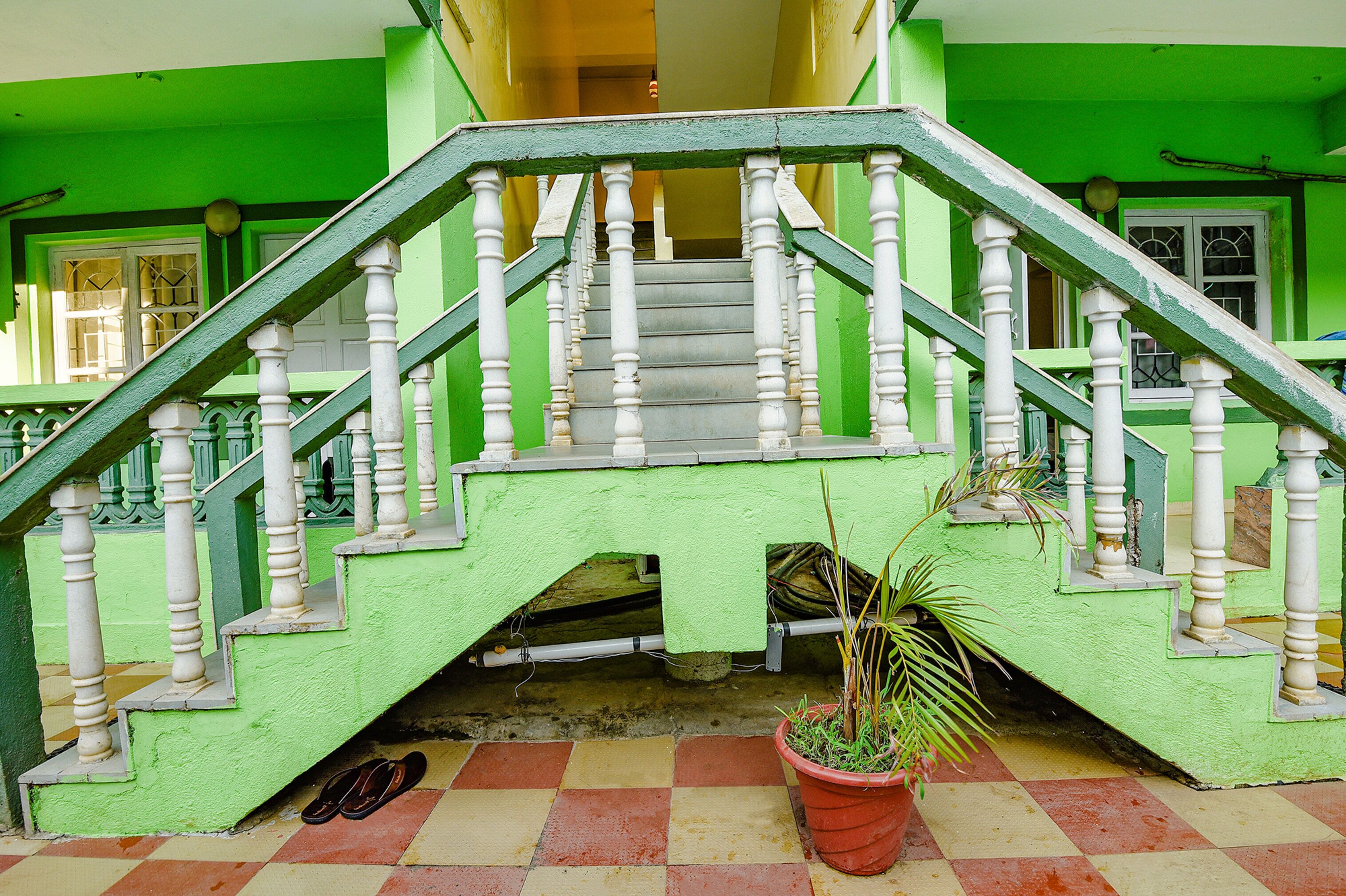 Uma escadaria com balaústres brancos e paredes verdes que leva a um andar superior.