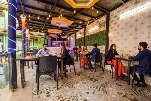 A restaurant with hexagonal ceiling lights, patterned floor tiles, and a green exterior wall.