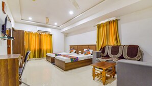 A hotel room with a bed, a sofa, a table, and a TV. - Fabexpress Radhe Residency (Ahmedabad)