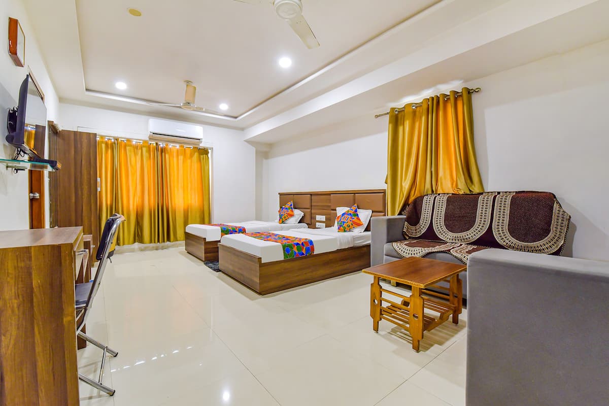 A hotel room with a bed, a sofa, a table, and a TV.