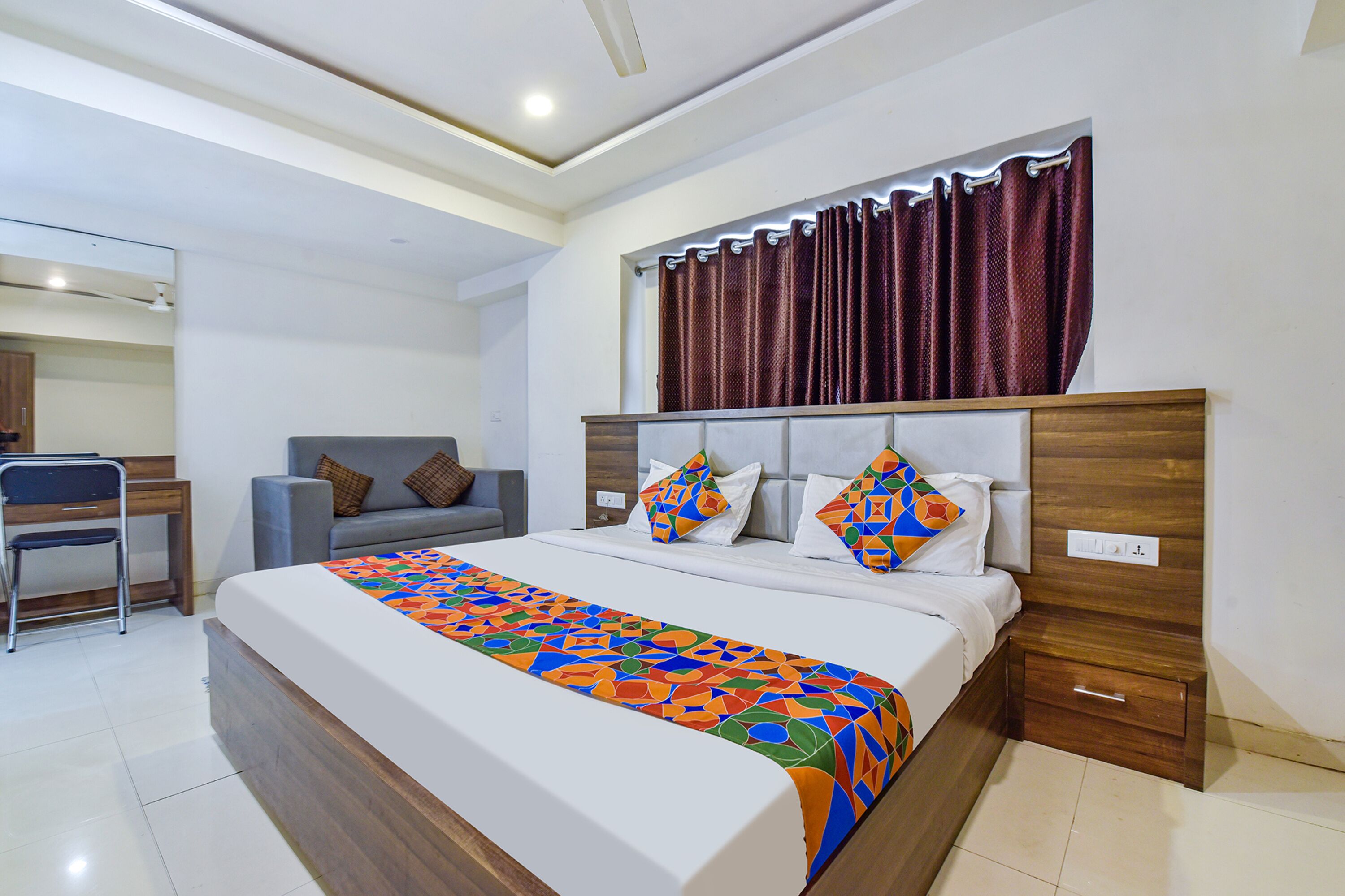 A modern hotel room with a large bed, a desk, and a chair.