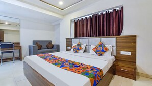 A modern hotel room with a large bed, a desk, and a chair. - Fabexpress Radhe Residency (Ahmedabad)