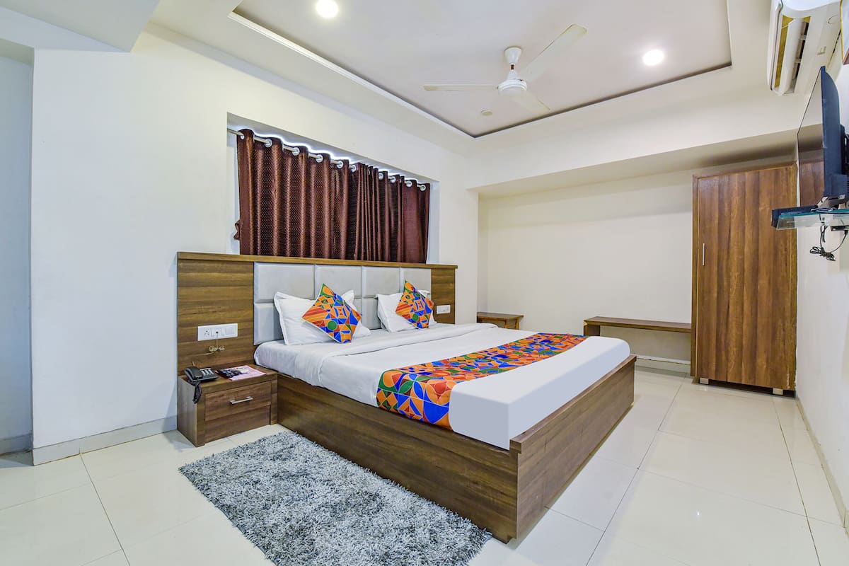 A bedroom with a wooden bed, a nightstand, a desk, a wardrobe, and a ceiling fan.