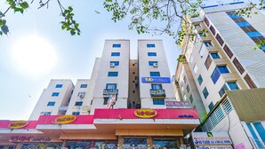 A multi-story building with various signs indicating hotels and businesses, including "Tab Hotels" and "Pakvan". - Fabexpress Radhe Residency (Ahmedabad)