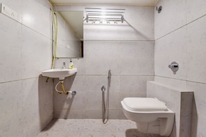 A small, modern bathroom with a white sink, toilet, and shower. - Fabexpress Radhe Residency (Ahmedabad)