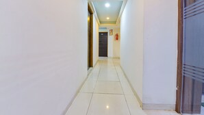 A narrow, well-lit hallway with white walls and a tiled floor, leading to a door marked with the number 302. - Fabexpress Radhe Residency (Ahmedabad)