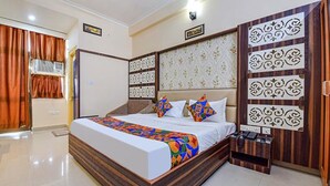 A bedroom with a wooden bed frame, a patterned headboard, and a bedside table with a telephone. - Fabhotel Aayojan (Jaipur)
