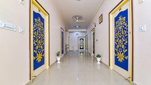 A hallway with decorative blue doors, white walls, and tiled flooring. - Fabhotel Aayojan (Jaipur)