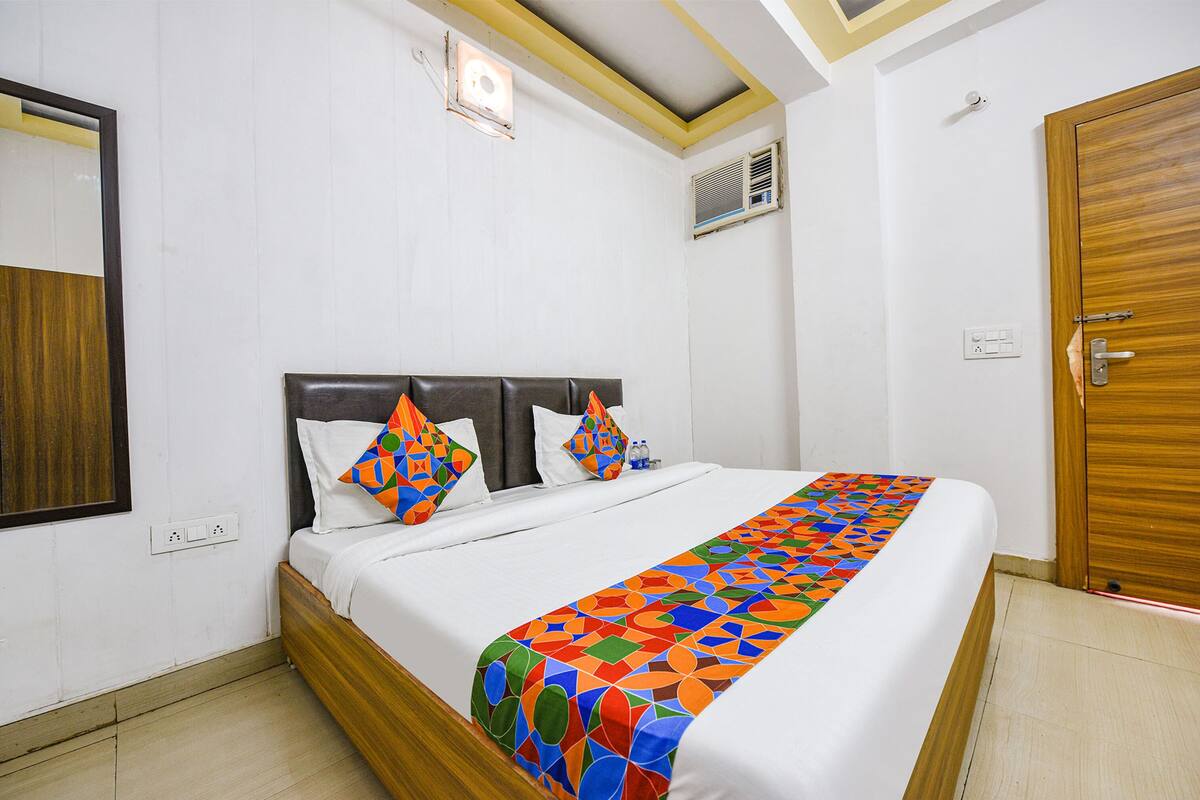 A neatly made bed with a colorful geometric-patterned bedspread, a wooden headboard, and two decorative pillows.