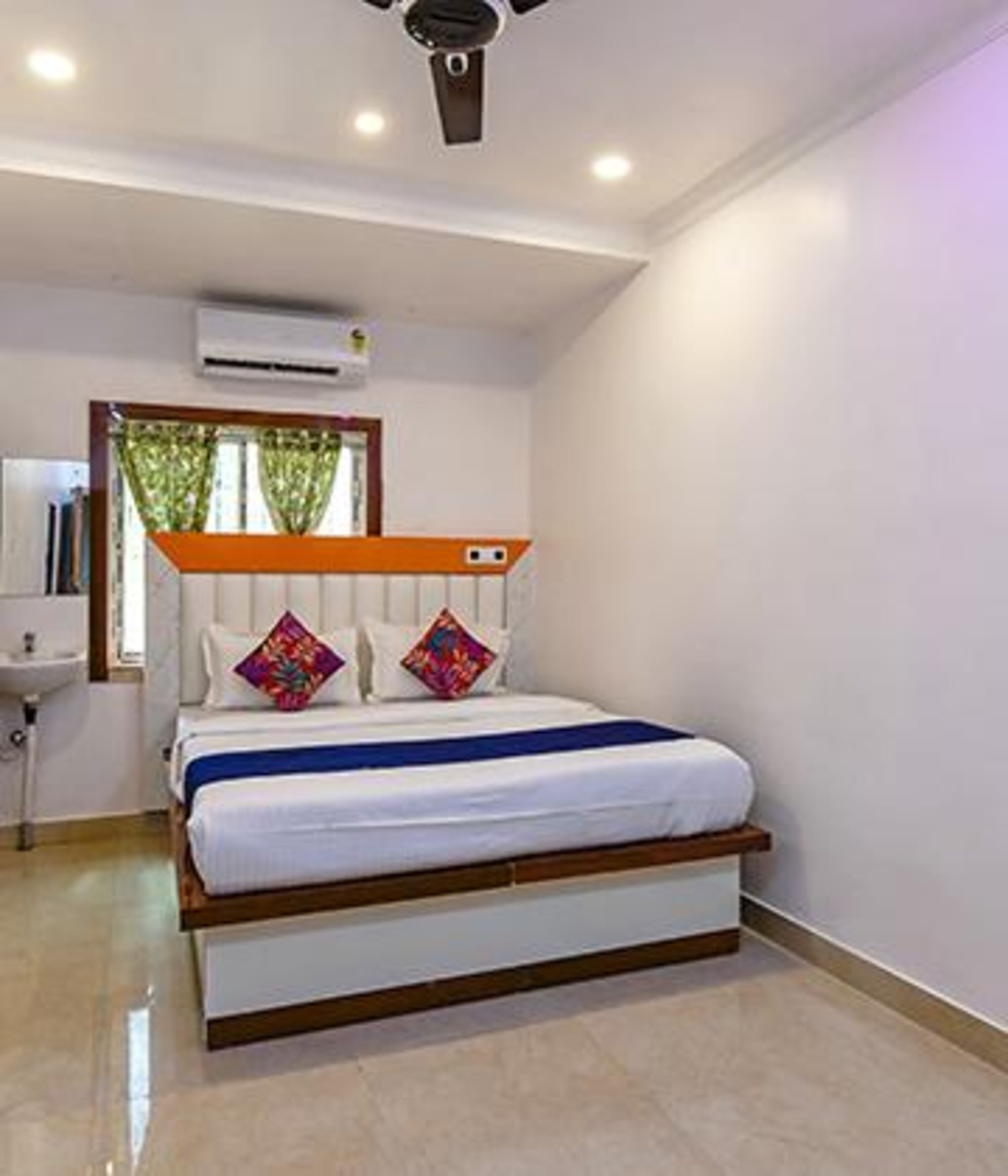 Une chambre à coucher avec un lit, un ventilateur de plafond, un appareil de climatisation et une fenêtre avec des rideaux.