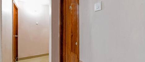 A hallway with a wooden door and a light switch on the wall.