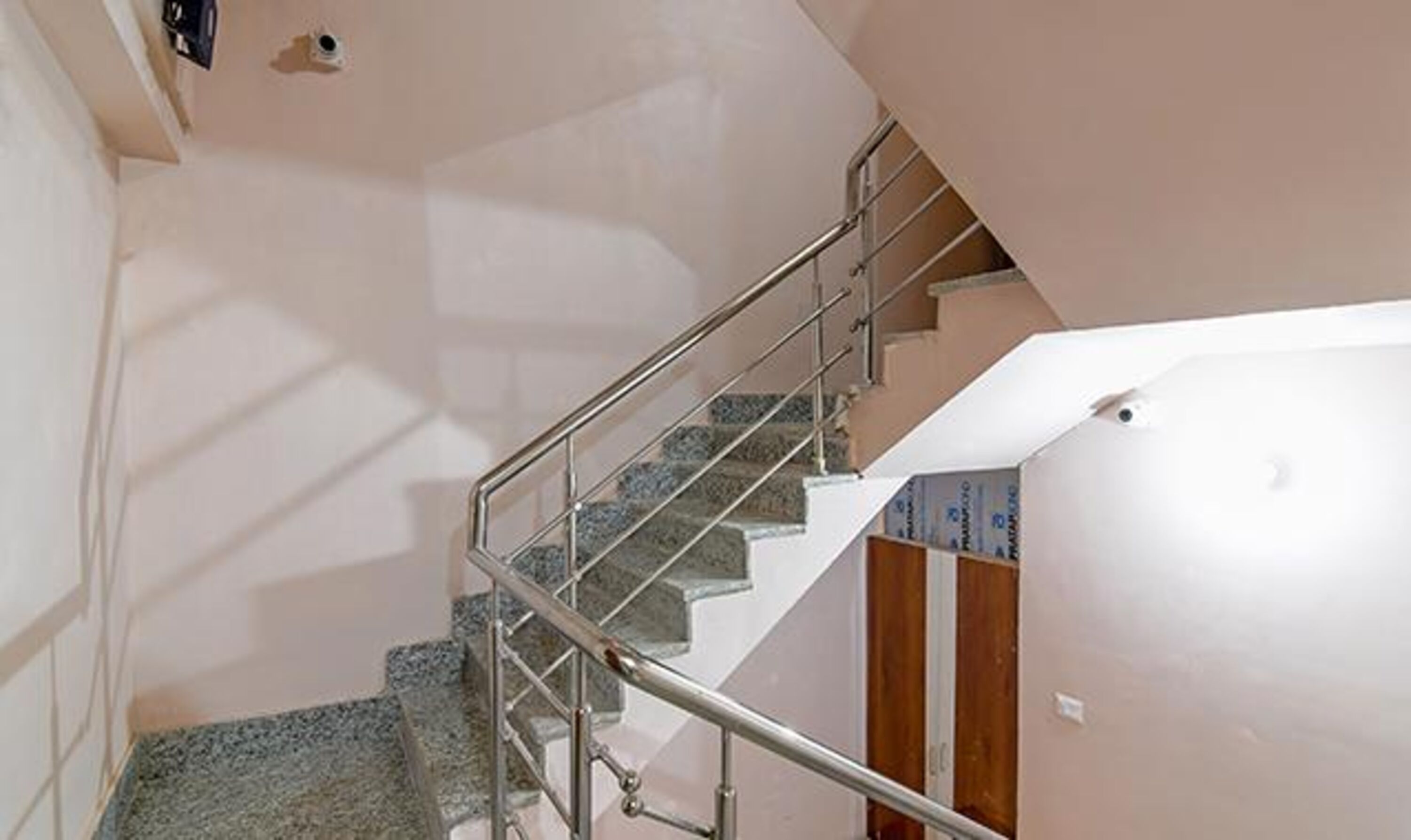 A staircase with metal railings, a wooden door, and a tiled wall.