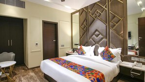 Camera d'albergo con un letto grande, un comodino con il telefono, un tavolino con una sedia e un armadio.
