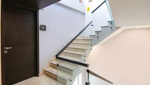 Una moderna scala con ringhiere in vetro e una porta in legno scuro.