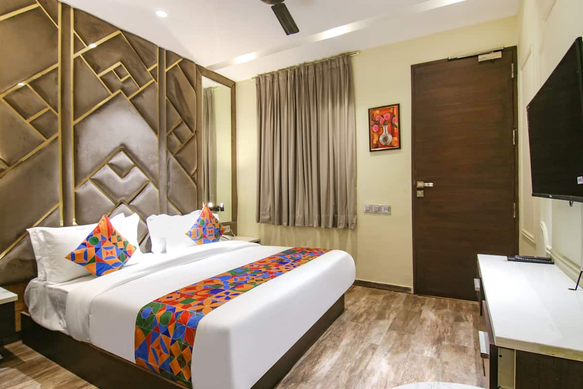 A hotel room with a large bed, a desk, a television, and a door.