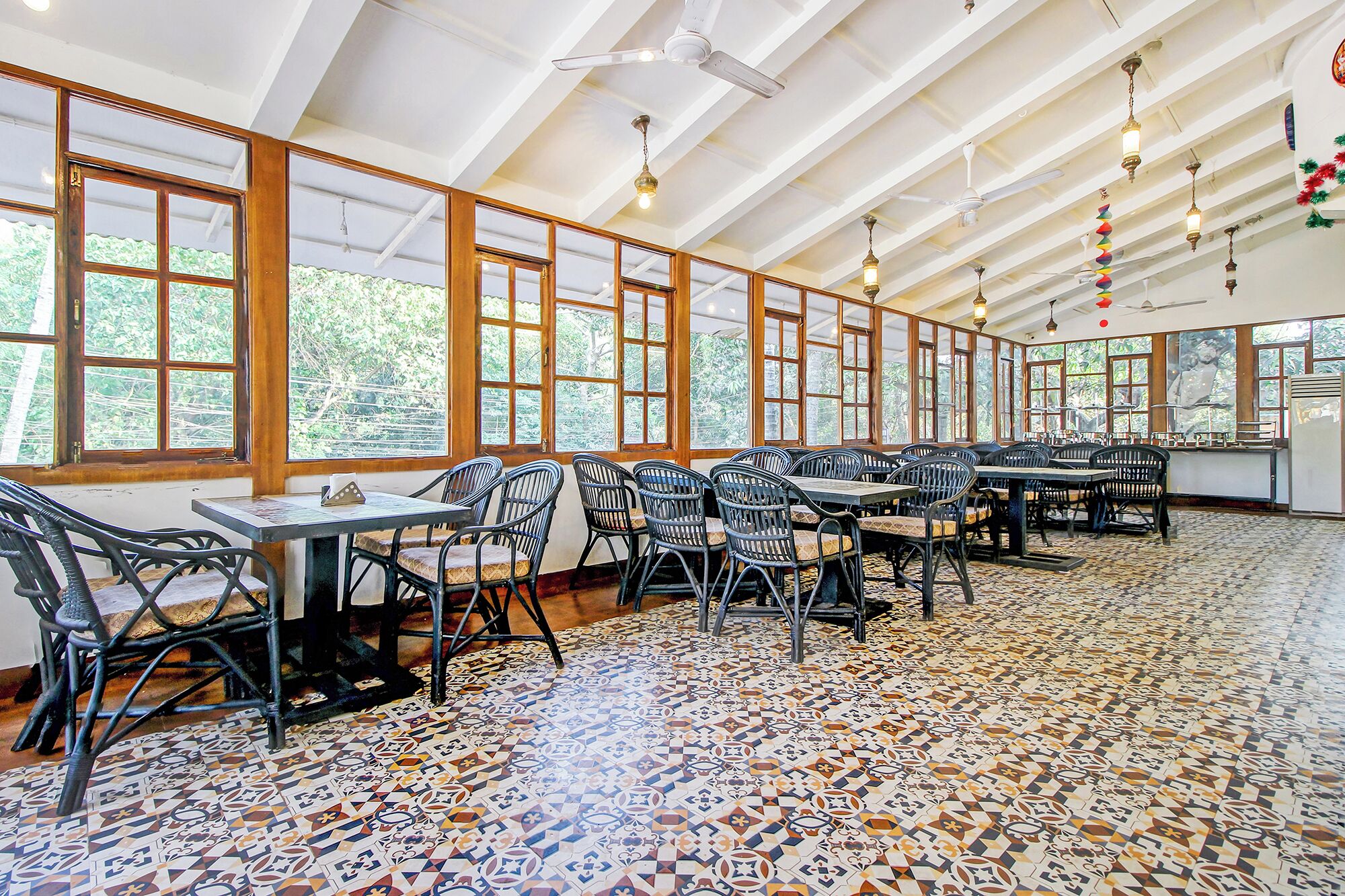 Une salle à manger spacieuse avec de hauts plafonds, de grandes fenêtres et des carreaux de sol décorés.