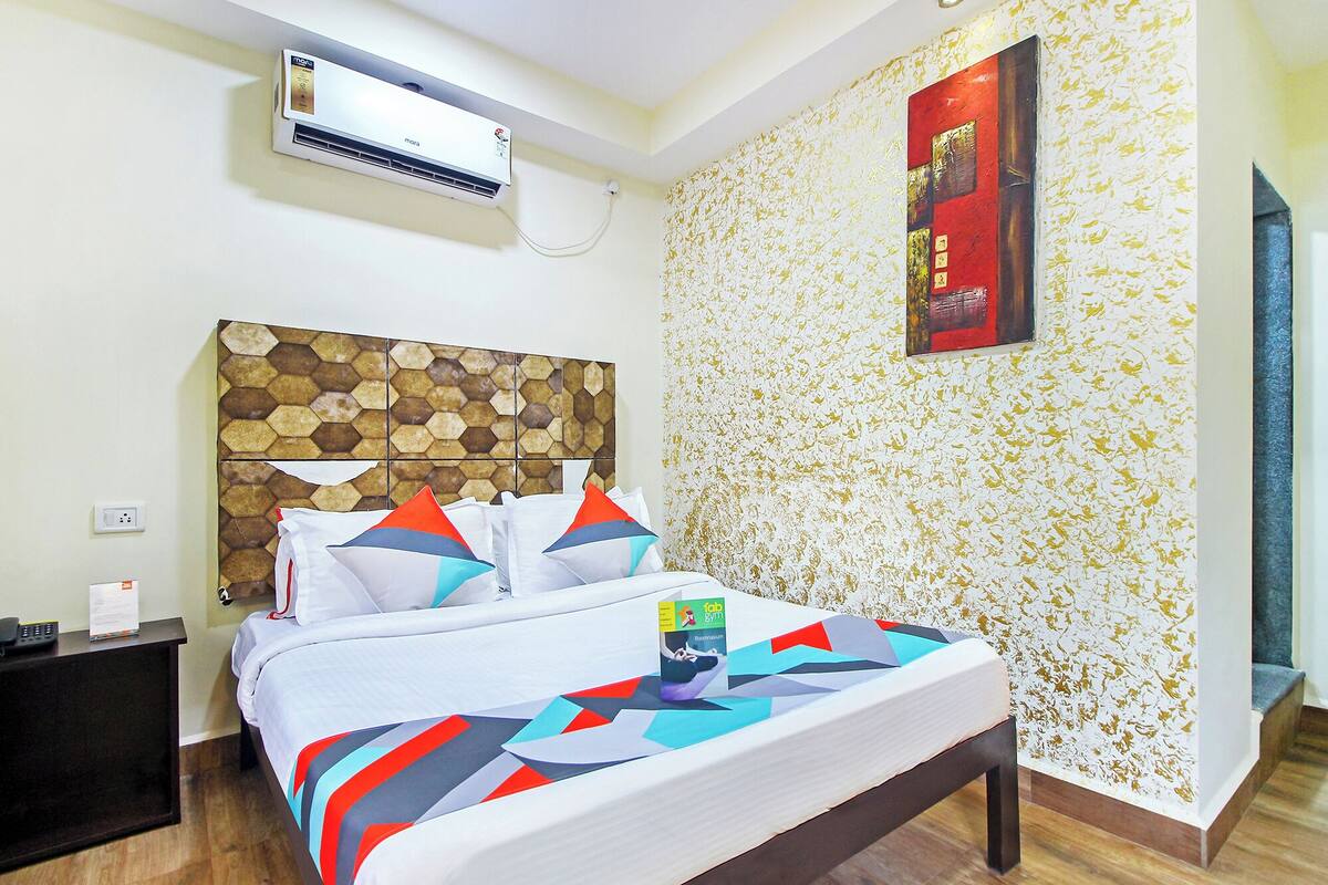 Ein Hotelzimmer mit Bett, Nachttisch, Klimaanlage, einer Wand mit Muster und einer Tür.