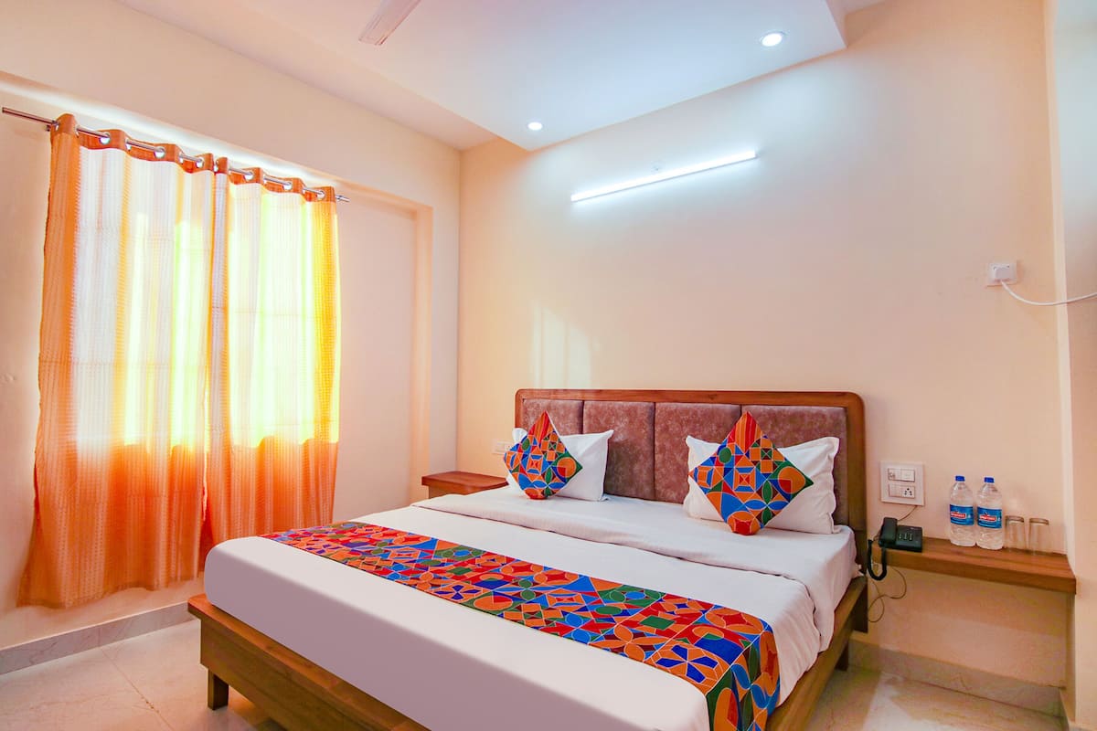 A neatly made bed with a colorful geometric-patterned bedspread, a wooden headboard, and two pillows with geometric patterns.
