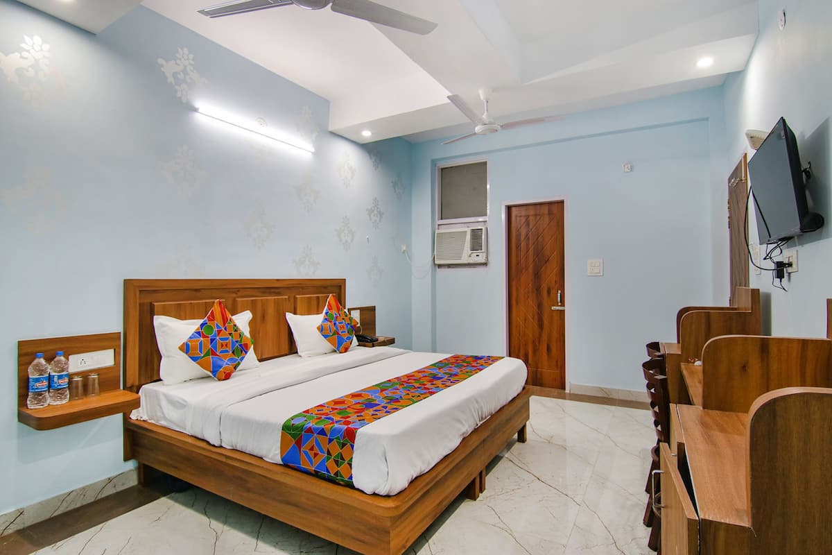 A hotel room with a wooden bed, a desk, a chair, a television, and a ceiling fan.