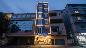Un edificio moderno con un letrero de 'fabHOTELS', que presenta una entrada central con fachada de vidrio y varias ventanas.