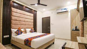 Una habitación de hotel con una cama grande, ventilador de techo, aire acondicionado y cabecero de madera.