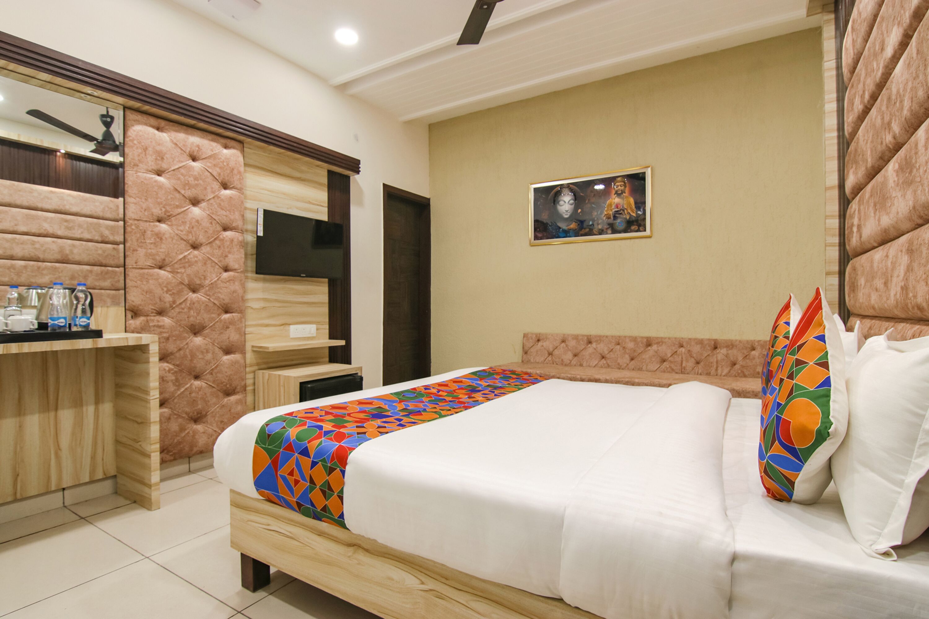A hotel room with a bed, a desk, and a television.