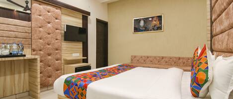 A hotel room with a bed, a desk, and a television.